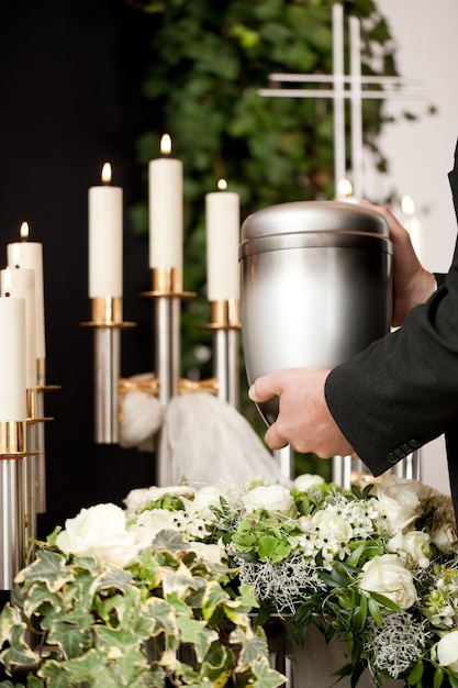 man-taking-funeral-urn-with-candles-flowers man-taking-funeral-urn-with-candles-flowers